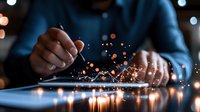Professional in business attire working on digital tablet with magical glowing sparkles and light effects emerging from screen in dark office environment.