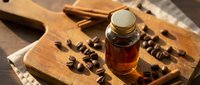 Amber glass bottle with natural honey on rustic wooden cutting board surrounded by coffee beans creating warm artisanal kitchen scene for organic food packaging.