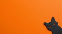 Black cat head silhouette with glowing eyes on vibrant orange background, isolated and ready for Halloween designs, greeting cards, and festive decorations.