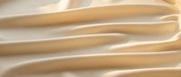 Smooth flowing beige silk fabric with elegant waves and soft lighting creating luxurious textile background for fashion and beauty projects.