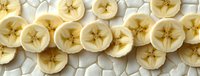 Fresh sliced banana rounds arranged in neat rows on white background, showing natural star pattern in center, creating appetizing healthy food pattern.