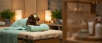 Relaxing spa treatment room with massage table, soft lighting, candles and towels creating peaceful wellness atmosphere for therapeutic sessions.