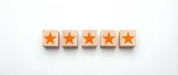 Five wooden blocks with orange stars arranged in row on white background for rating feedback and customer satisfaction evaluation concepts.