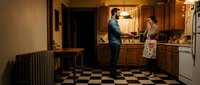 Young couple cooking together in vintage kitchen with checkered floor and warm lighting creating cozy domestic atmosphere for home lifestyle content.