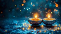 Two decorative oil lamps with burning flames on blue textured surface with bokeh lights in background creating festive Diwali atmosphere.