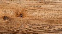 Natural oak wood grain texture with distinctive knots and swirling patterns showcasing rich golden brown tones and organic lines, suitable for interior design projects.