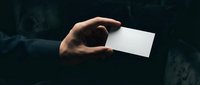 Hand holding blank white business card mockup against dark background for branding and corporate identity design projects.