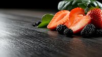 Sliced salmon fillet with fresh blackberries, strawberries, and mint leaves arranged on dark wooden surface for culinary and food styling projects.