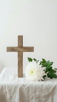 Wooden cross with white chrysanthemum flower on linen cloth for Easter memorial service funeral condolence sympathy religious faith spiritual worship.