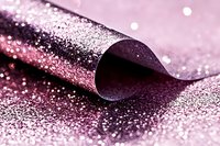 Curled edge of glittery pink metallic paper with scattered sparkles and bokeh effects creating luxurious festive backdrop for holiday designs and celebrations.