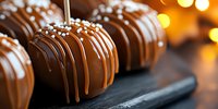 Chocolate confections with white pearl sprinkles arranged on dark slate, warm bokeh background. Gourmet desserts for bakery, patisserie, confectionery, and food styling projects.
