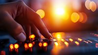 Hand adjusting illuminated orange LED string lights creating magical bokeh effect against dark background, warm ambient lighting for festive holiday atmosphere.