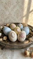 Elegant vintage Easter eggs with floral patterns and clock motifs arranged in ornate metal basket on damask wallpaper background for spring holiday decor.