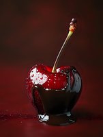 Fresh ripe cherry covered in dark chocolate with water drops on dark red background, dramatic lighting creates luxurious dessert atmosphere.