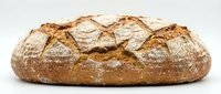 Freshly baked artisan sourdough bread loaf with golden crust and rustic scoring patterns isolated on white background for bakery and food design projects.
