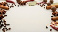 Aromatic spices frame with cinnamon sticks, star anise, cloves, nutmeg and chili peppers on white background. Copy space for culinary design projects.