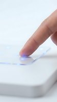 Human finger touching illuminated smartphone screen with blue light glow on white background for technology and digital interaction concepts.