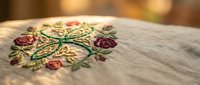 Colorful floral embroidery with roses and leaves on natural linen fabric, traditional needlework craft for home decor and textile design projects.