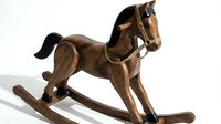 Vintage wooden rocking horse with dark mane and leather harness, isolated on white background, classic handcrafted toy for nursery decor.
