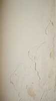 Weathered cream wall with peeling paint and cracked plaster surface, suitable for backgrounds, textures, and design projects requiring aged or distressed wall elements.