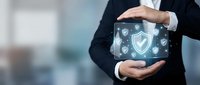 Professional businessman in dark suit protecting digital security shield with hands showing cybersecurity and data protection concept for business technology.