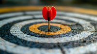 Red dart arrow hitting bullseye target center on textured dartboard, close-up view with selective focus showing success and achievement in business goals.