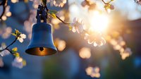 Bronze bell hanging among blooming cherry blossoms at sunset, creating magical bokeh effect with soft focus petals and golden sunlight streaming through branches.