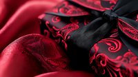 Red satin corset with black lace trim and ribbon detail, featuring ornate baroque pattern design, close-up view showing luxurious fabric texture and intricate embellishments.