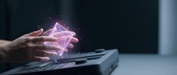 Young adult hand holding glowing pink holographic pyramid above laptop keyboard, representing digital technology, artificial intelligence, and futuristic innovation for tech concepts.
