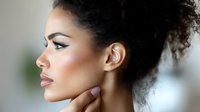 Young African American woman with natural curly hair in profile view against blurred background, showcasing elegant makeup and glowing skin for beauty and cosmetic advertising.