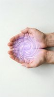 Cupped hands holding glowing purple energy spiral for healing, wellness, and spiritual practices on neutral background.