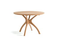 Round wooden dining table with elegant curved pedestal base featuring organic branching legs in natural oak finish, isolated on white background.