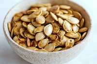 Roasted peanuts in ceramic bowl on white background, healthy snack for cooking, baking, or nutritional content use.
