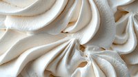 Creamy white meringue swirls with soft peaks and delicate texture, perfect for dessert decoration or bakery photography.