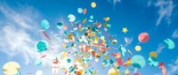 Colorful balloons and confetti floating in bright blue sky with white clouds creating festive celebration atmosphere for parties and joyful events.