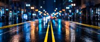 Wet asphalt road with yellow dividing line at night, illuminated by colorful bokeh lights from street lamps and traffic, creating atmospheric urban scene.
