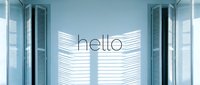 Bright minimal interior with open shuttered windows casting shadow patterns on white wall with hello text, fresh welcoming atmosphere.