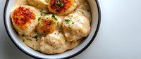 Pan-seared scallops in creamy garlic sauce garnished with fresh herbs and black pepper, served in white ceramic bowl on light background.