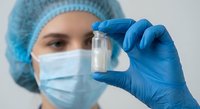 Female scientist in protective gear examining test tube sample in laboratory research environment for medical analysis and pharmaceutical development.