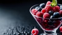 Fresh mixed berries with mint in glass bowl on dark background for healthy eating and dessert recipes.