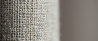 Natural beige linen fabric texture with woven fibers in soft focus. Close-up macro shot showing textile weave pattern for interior design and crafting projects.