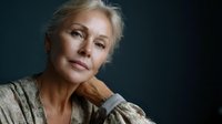 Confident mature Caucasian woman with gray hair in contemplative pose against dark background for lifestyle and aging gracefully concepts.