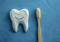 Smiling tooth-shaped soap and bamboo toothbrush on textured blue background for dental hygiene promotion and eco-friendly oral care concept.