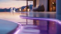Modern curved bar counter illuminated with purple LED strip lighting creates atmospheric mood in luxurious restaurant interior during evening hours.