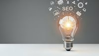 Light bulb with SEO icons and digital marketing symbols floating above, representing creative optimization strategies and search engine concepts.