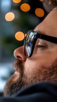 Close-up profile of bearded man wearing sunglasses with city lights reflection, soft bokeh background creates dreamy atmosphere, shallow depth of field.