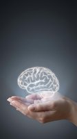 Glowing brain hologram floating above open palm representing artificial intelligence, mental health, neuroscience and cognitive thinking concepts.