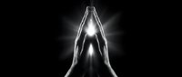 Two hands pressed together in prayer position with glowing light emanating from between palms against dark background, symbolizing spirituality, hope, faith, meditation, and inner peace for wellness and mindfulness designs.