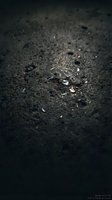Dark asphalt road surface with scattered debris and gravel fragments creating textured pavement background for urban transportation concepts.