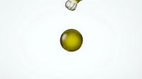 Olive oil droplet falling onto white surface with golden liquid sphere in motion, suitable for food, cooking, and wellness product marketing.